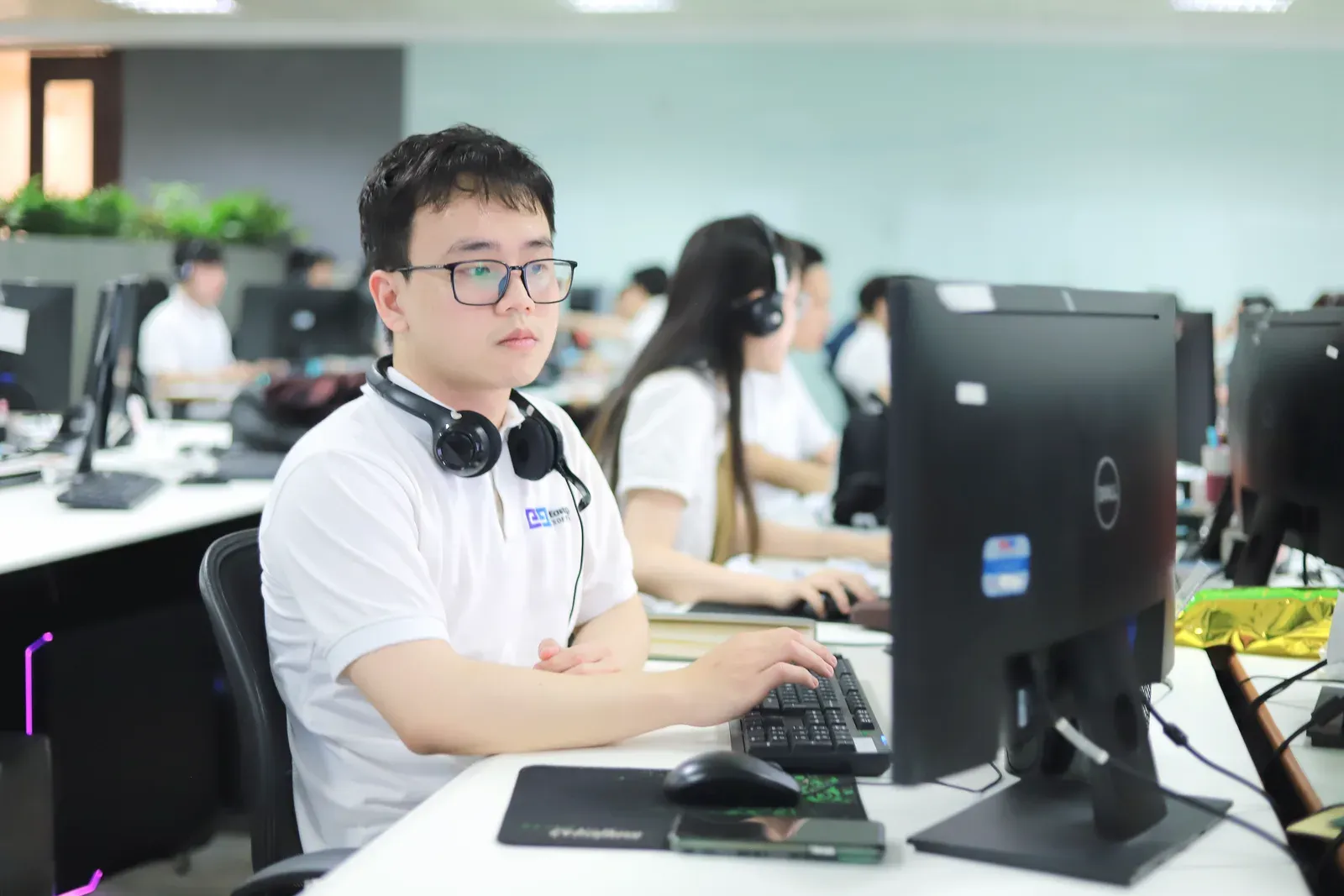 An engineer with a headset working at a desk in an open-plan office