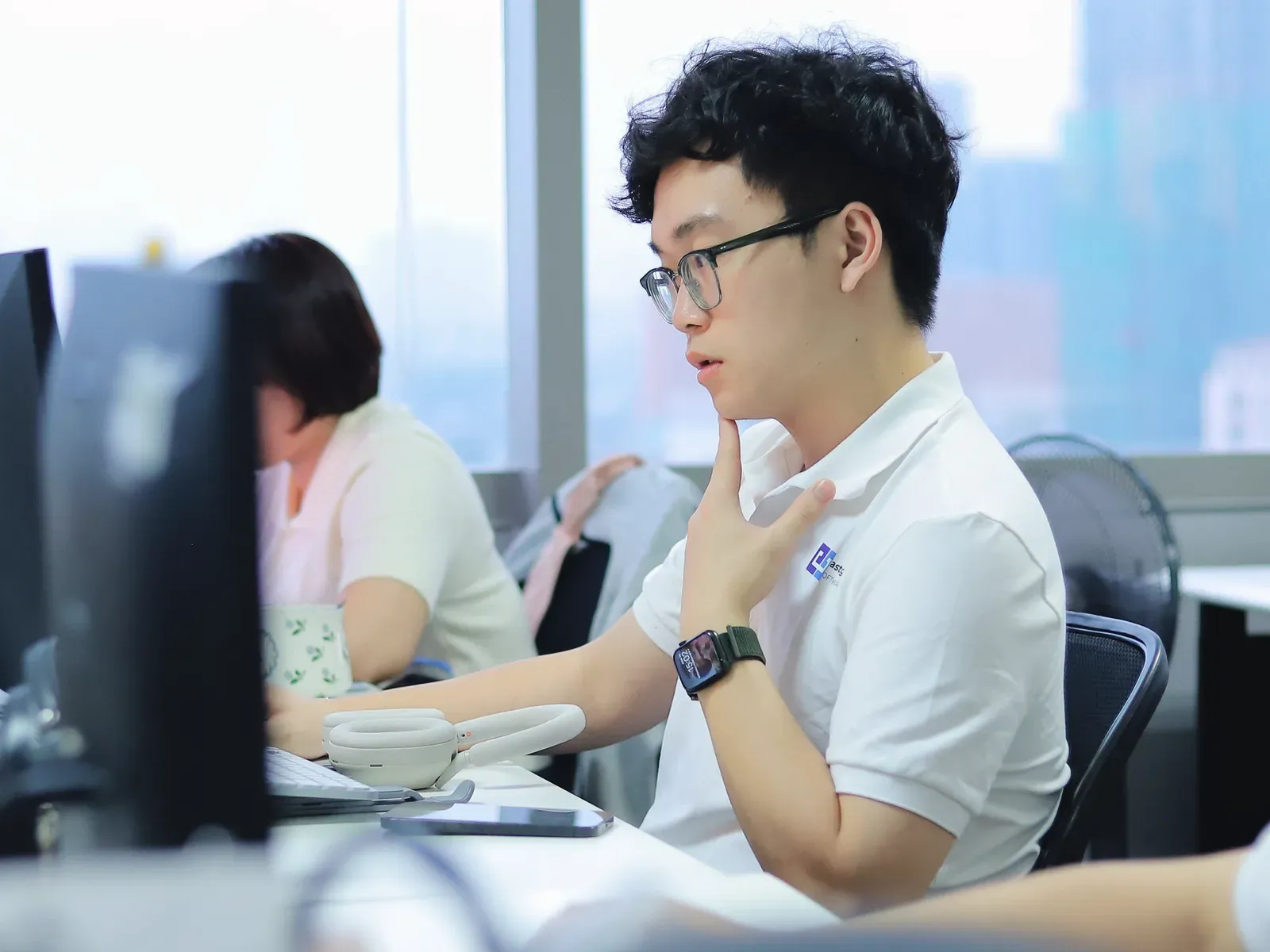 An engineer at his desk, hand on chin, thinking through a problem