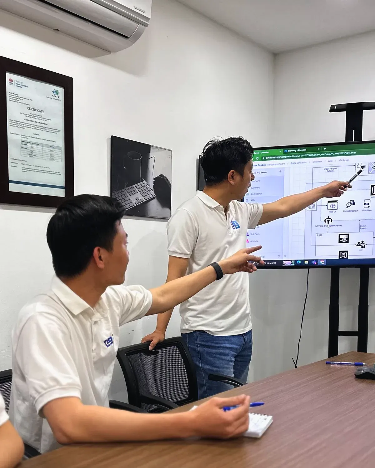 Two engineers reviewing a process diagram on a large screen