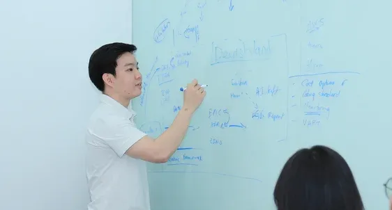 An engineer writing a system design diagram on a whiteboard during a planning session.