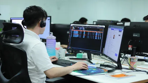 Engineer working at a dual-monitor development setup in an open office