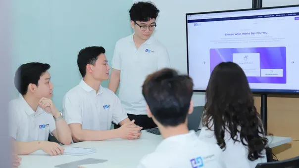 Engineers in a workshop discussing a product screen shown on a large display