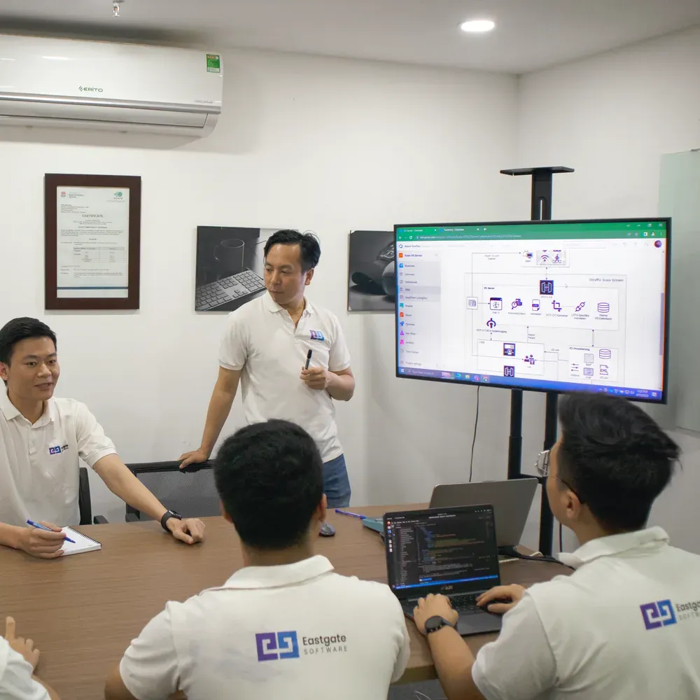 An Eastgate engineer walking colleagues through a system diagram on a wall screen in a meeting room