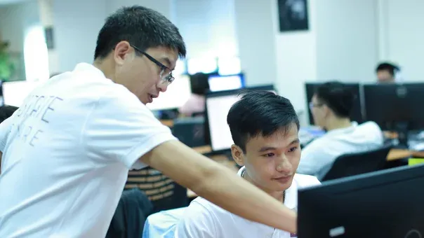 Two engineers reviewing code together on a monitor